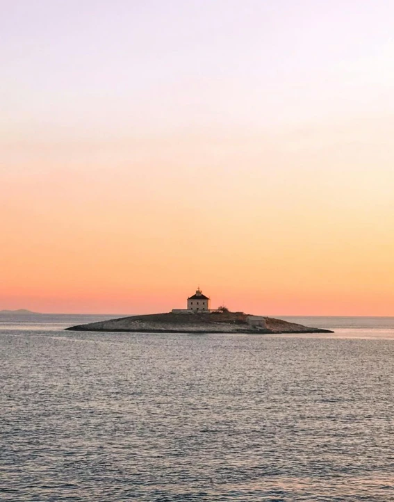 a lighthouse on a small island in the middle of the ocean, inspired by Wilhelm Marstrand, unsplash contest winner, pastel orange sunset, minna sundberg, slightly tanned, conde nast traveler photo