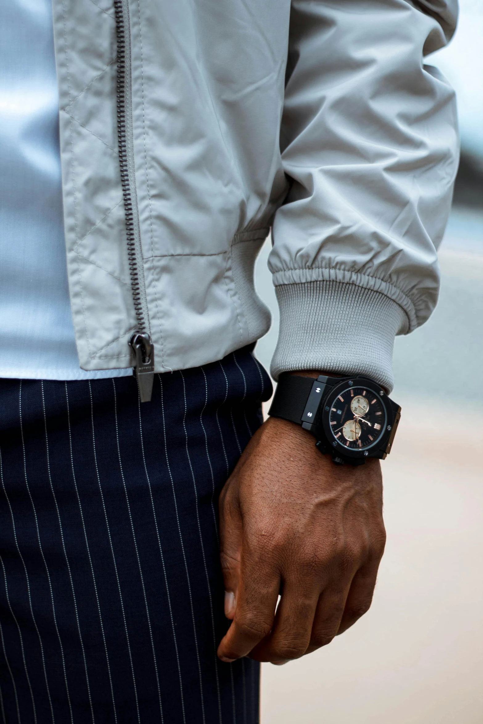 a close up of a person wearing a watch, inspired by Eugène Brands, an aviator jacket and jorts, wearing black grey suit, high technical detail, urban surroundings