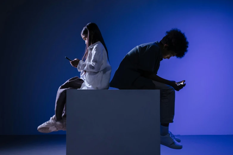 a man and a woman sitting on a cube looking at their phones, trending on pexels, realism, lowkey lighting, avatar image, teenagers, trending on mentalray