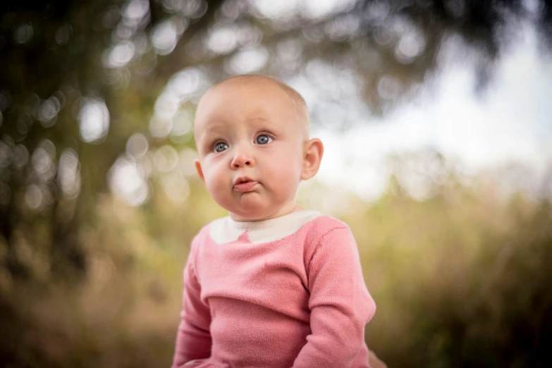 a baby sitting on top of a wooden bench, a portrait, by Jesper Knudsen, pexels contest winner, pink nose, she has a distant expression, at the park, portrait close - up