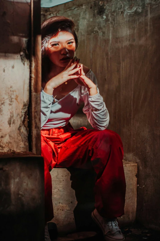 a woman sitting on top of a wooden bench, a portrait, inspired by Steve McCurry, pexels contest winner, hyperrealism, red clothes, sitting in a dark prison cell, 8 0 s asian neon movie still, vietnamese woman