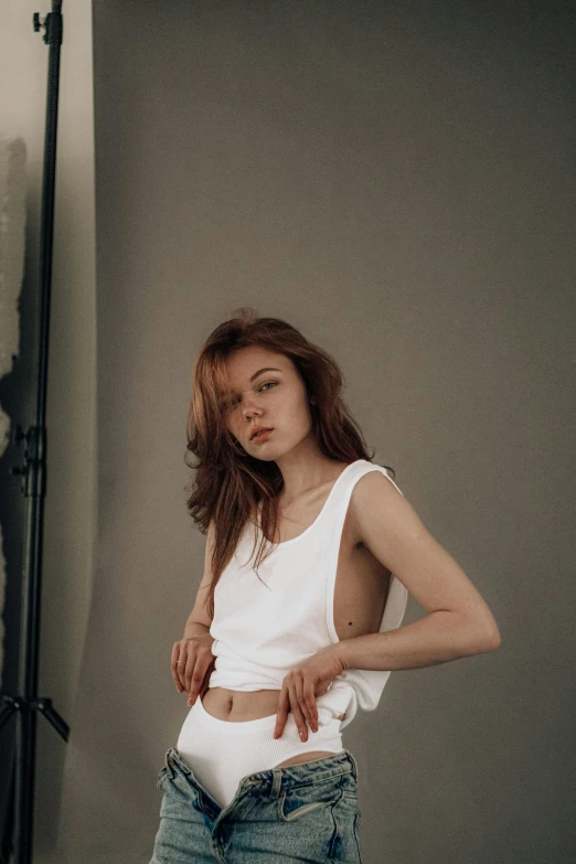 a beautiful young woman standing in front of a camera, a picture, inspired by Elsa Bleda, trending on pexels, renaissance, white long tanktop, short redhead, ripped up white garment, anna nikonova aka newmilky