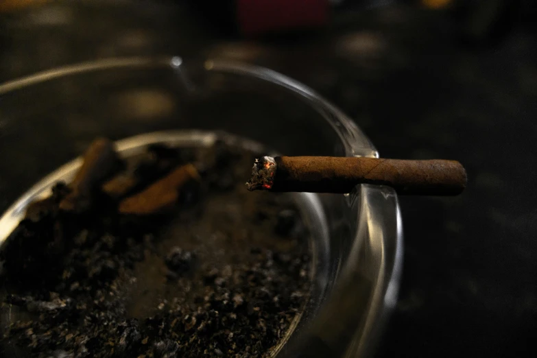 a close up of a cigarette in a ashtray, an album cover, inspired by Elsa Bleda, unsplash, hyperrealism, nightcap, joints, almost black, taken with sony alpha 9