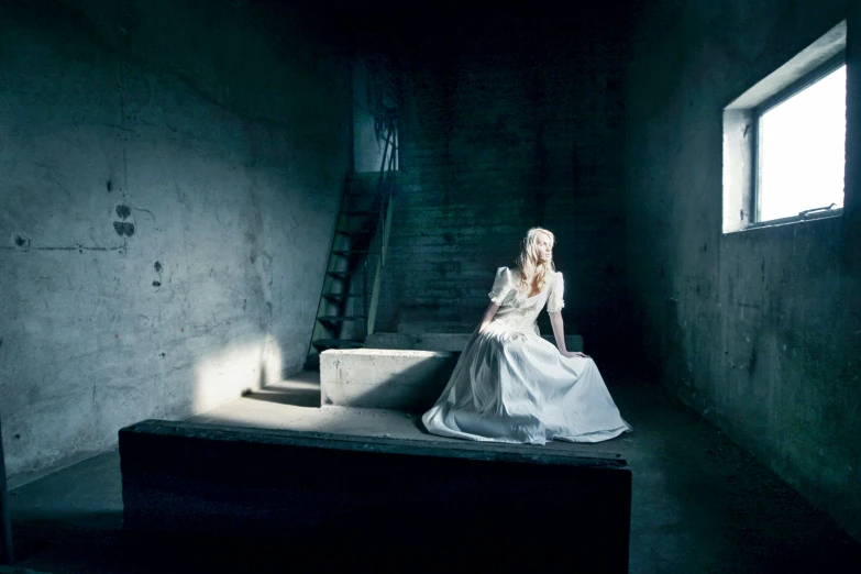 a woman in a white dress sitting on a bench, an album cover, inspired by Gottfried Helnwein, in a dark warehouse, kerli koiv, vermeer lighting, movie filmstill