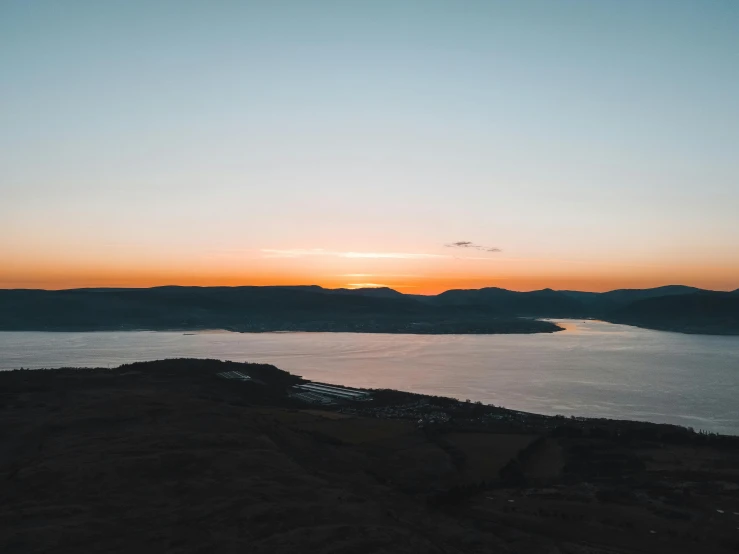 the sun is setting over a large body of water, by Daniel Lieske, pexels contest winner, black mountains, view from slightly above, conor walton, slightly pixelated