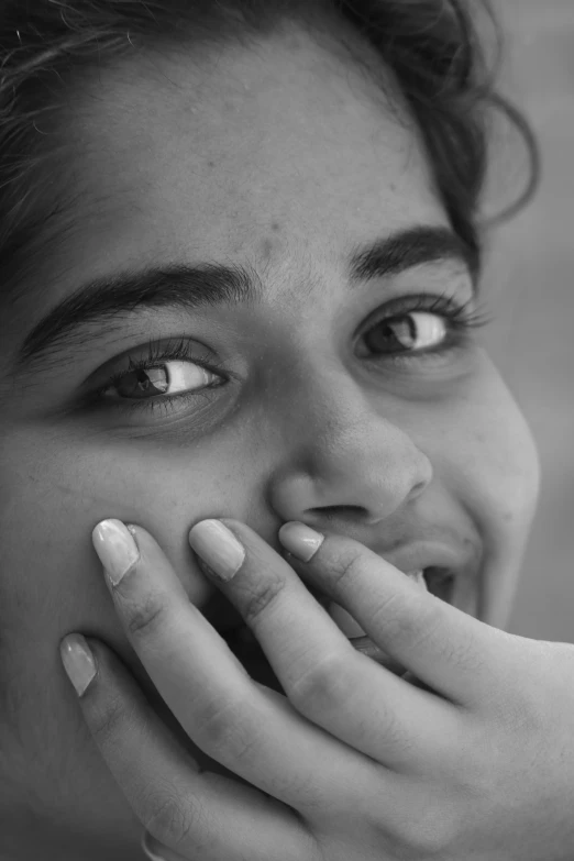 a black and white photo of a woman holding her hand to her mouth, inspired by irakli nadar, flickr, happy smiling human eyes, indian girl with brown skin, closeup at the faces, dreaming face