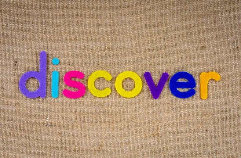 the word discover spelled in colorful wooden letters, by John Covert, promo image, hessian cloth, discovery zone, background image