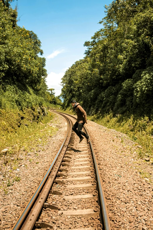 a man riding a skateboard down a train track, an album cover, inspired by Steve McCurry, sumatraism, solo hiking in mountains trees, snapchat photo, jamaica, doing a sassy pose