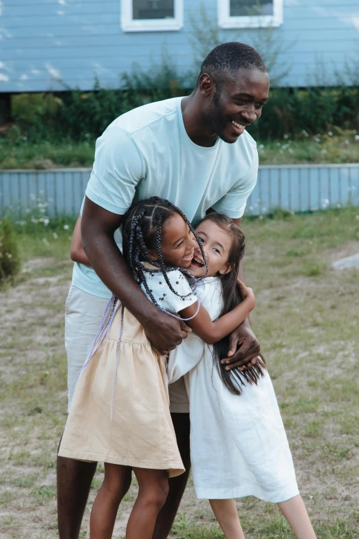 a man standing next to two little girls, pexels contest winner, happening, jaylen brown, holding each other, ( ( theatrical ) ), summer setting