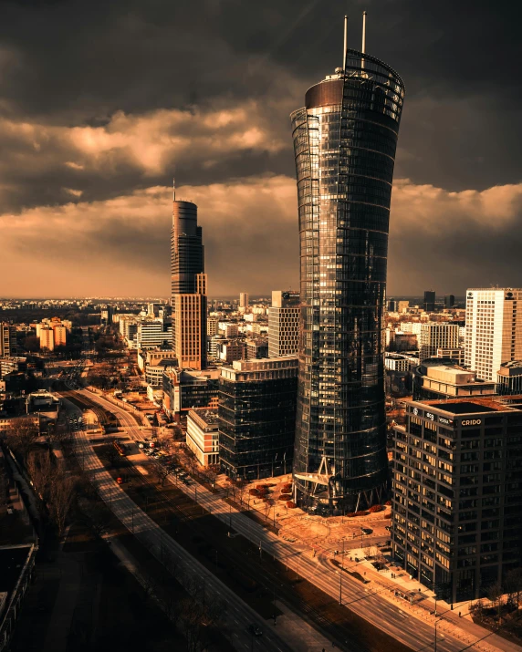 a very tall building sitting in the middle of a city, by Adam Marczyński, pexels contest winner, koyaanisqatsi, an image of a tornado, warsaw, two organic looking towers