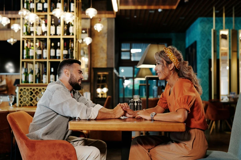 a man and a woman sitting at a table, by Lee Loughridge, pexels contest winner, te pae, flirty, middle eastern, casually dressed