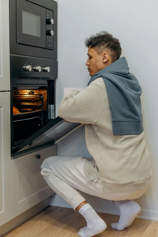 a man squatting down in front of an oven, profile image, comforting, technical, wearing pajamas