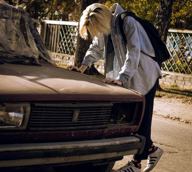 a woman leaning over the hood of a car, inspired by Elsa Bleda, pexels contest winner, graffiti, young blonde boy fantasy thief, a wooden, moskvich, head down