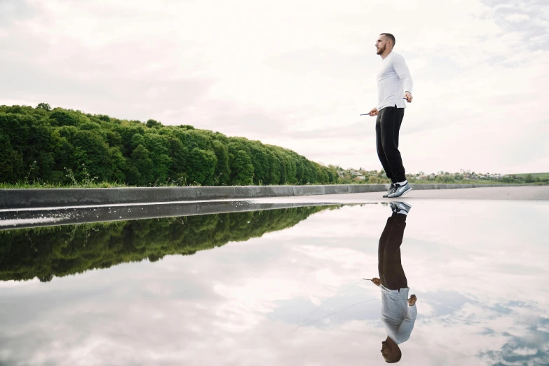 a man standing in front of a body of water, happening, reflective floor, cloud jumper, running, sydney park