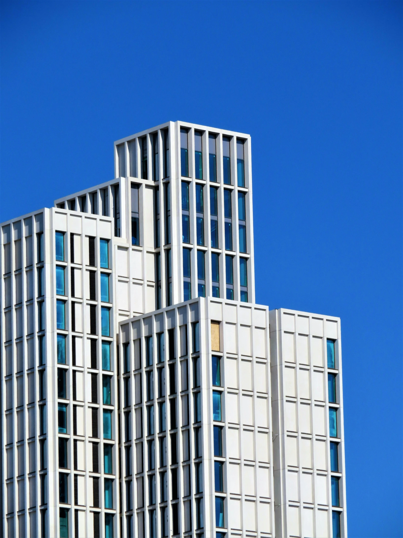 a tall building with a clock on top of it, inspired by David Chipperfield, unsplash, white and pale blue, modular, iron cladding, architecture award winning