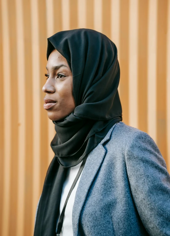 a woman standing in front of a wooden wall, inspired by Maryam Hashemi, trending on unsplash, wrapped in a black scarf, beautiful city black woman only, minna sundberg, photographed for reuters