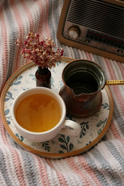 a cup of tea on a plate next to a radio, inspired by Elsa Bleda, instagram, folk art, promo image, ocher, cozy wallpaper, square