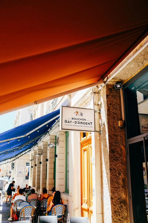 a group of people sitting outside of a restaurant, inspired by Barthélemy Menn, trending on unsplash, awnings, orange roof, old signs, bath