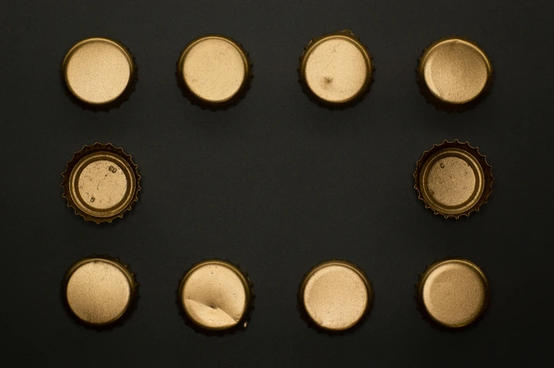 a bunch of bottle caps sitting on top of a table, a microscopic photo, by Ottó Baditz, pexels, visual art, black and gold, centered in panel, dividing it into nine quarters, view from slightly above