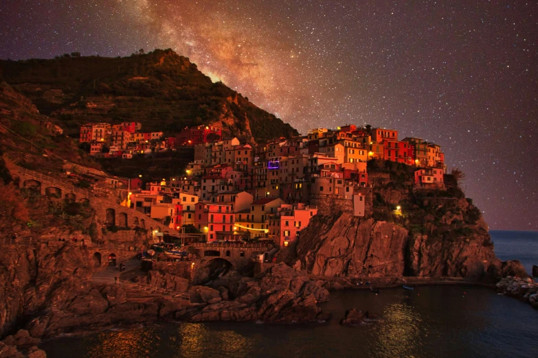 a town sitting on top of a hill next to the ocean, a matte painting, by Carlo Martini, pexels contest winner, renaissance, colorful night sky, cinq terre, youtube thumbnail, milkyway light