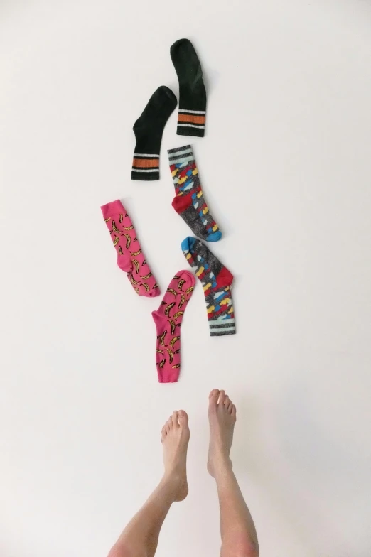 a woman laying on top of a bed next to a pair of socks, inspired by Weiwei, vibrant patterns, wide overhead shot, moma, standing on a shelf