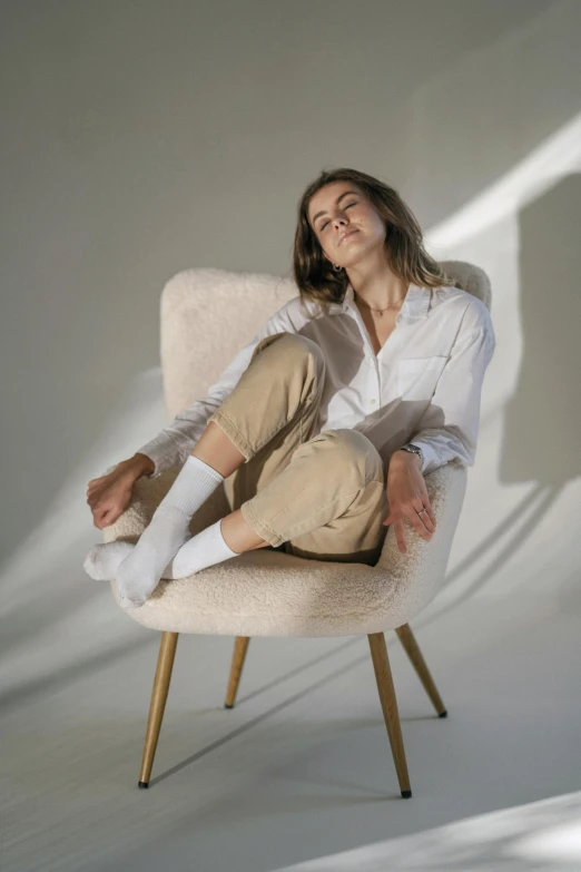 a woman sitting on a chair in a white room, inspired by Constantin Hansen, trending on unsplash, wearing cargo pants, chilled out smirk on face, beautifully soft lit, armchair