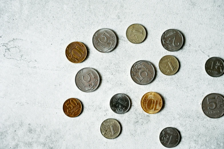 a group of coins sitting on top of a white surface, by Emma Andijewska, pexels contest winner, dau-al-set, gray concrete, slavic, vintage inspired, small