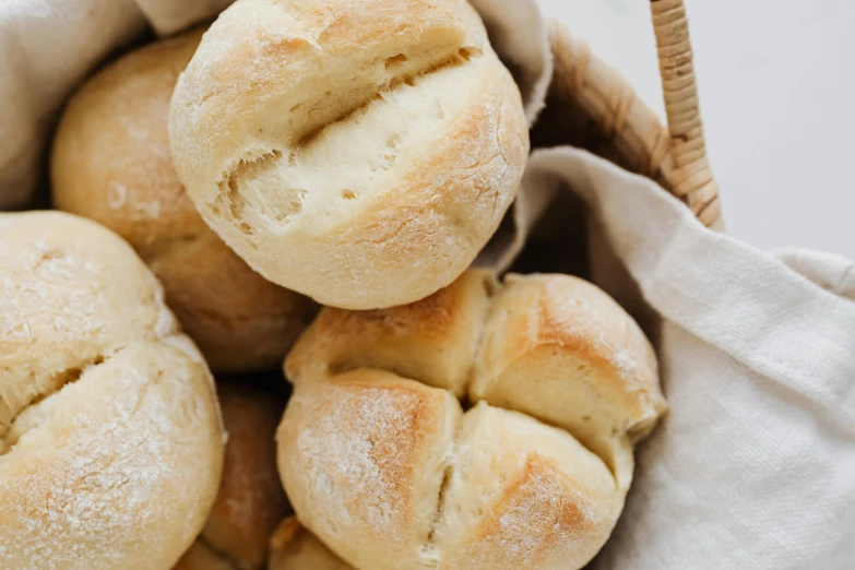 a basket filled with rolls of bread sitting on top of a table, by Emma Andijewska, trending on pexels, cream, middle close up, bao pnan, recipe