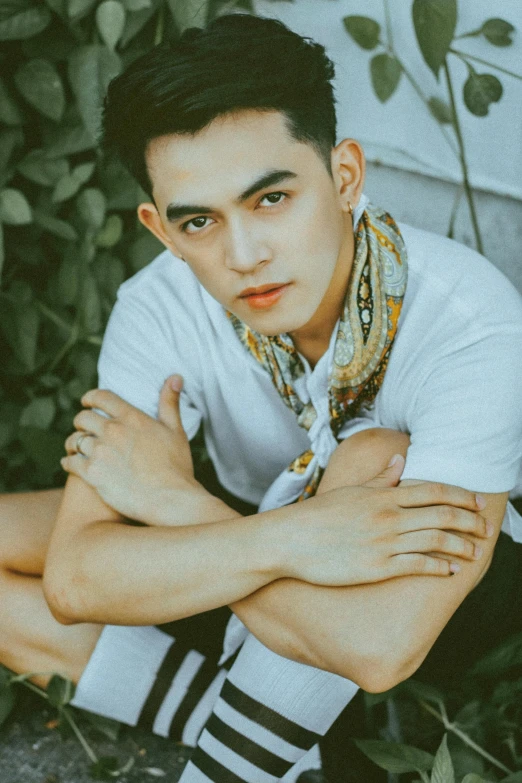 a man sitting on the ground with his arms crossed, a picture, inspired by Robbie Trevino, trending on pexels, portrait of modern darna, non binary model, patiphan sottiwilai, headshot profile picture