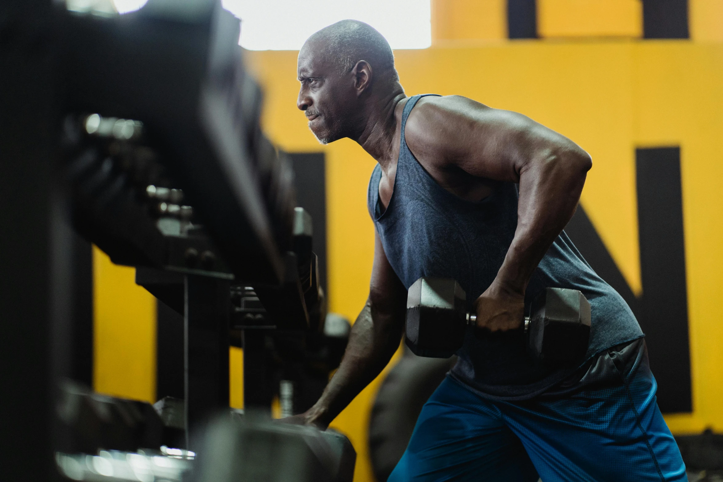 a man lifting a barbell in a gym, by Dan Luvisi, pexels contest winner, yellow and charcoal, profile image, aged 4 0, godwin akpan