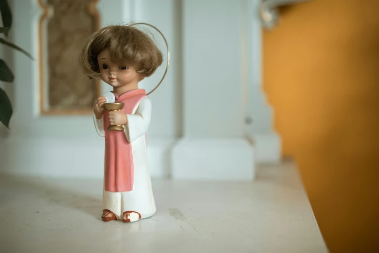 a close up of a figurine of a child, inspired by Louis Le Nain, unsplash, standing in a church, pink iconic character, male with halo, indoor picture