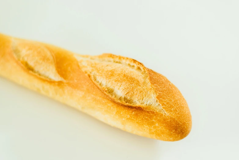 a long loaf of bread sitting on top of a table, pointé pose;pursed lips, plain background, very crisp, shot on 70mm