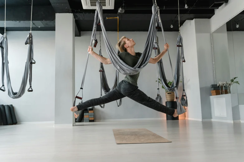 a woman doing a yoga pose on a hammock, by Emma Andijewska, arabesque, neo kyiv, low quality photo, full body hero, open room