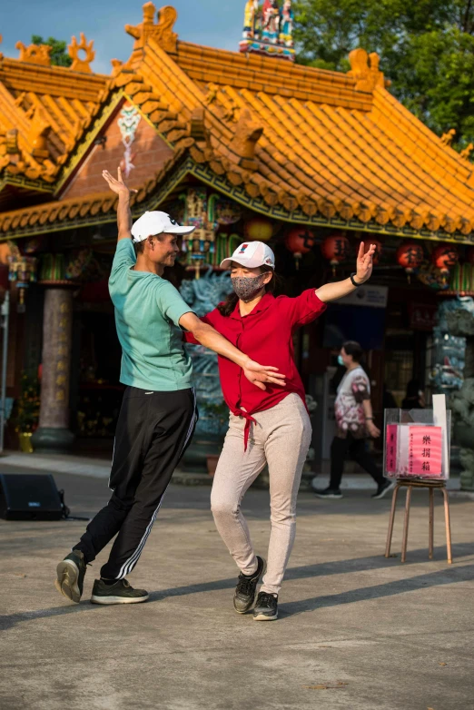 a couple of people that are standing in the street, he is dancing, with a chinese temple, dynamic skating, lgbtq