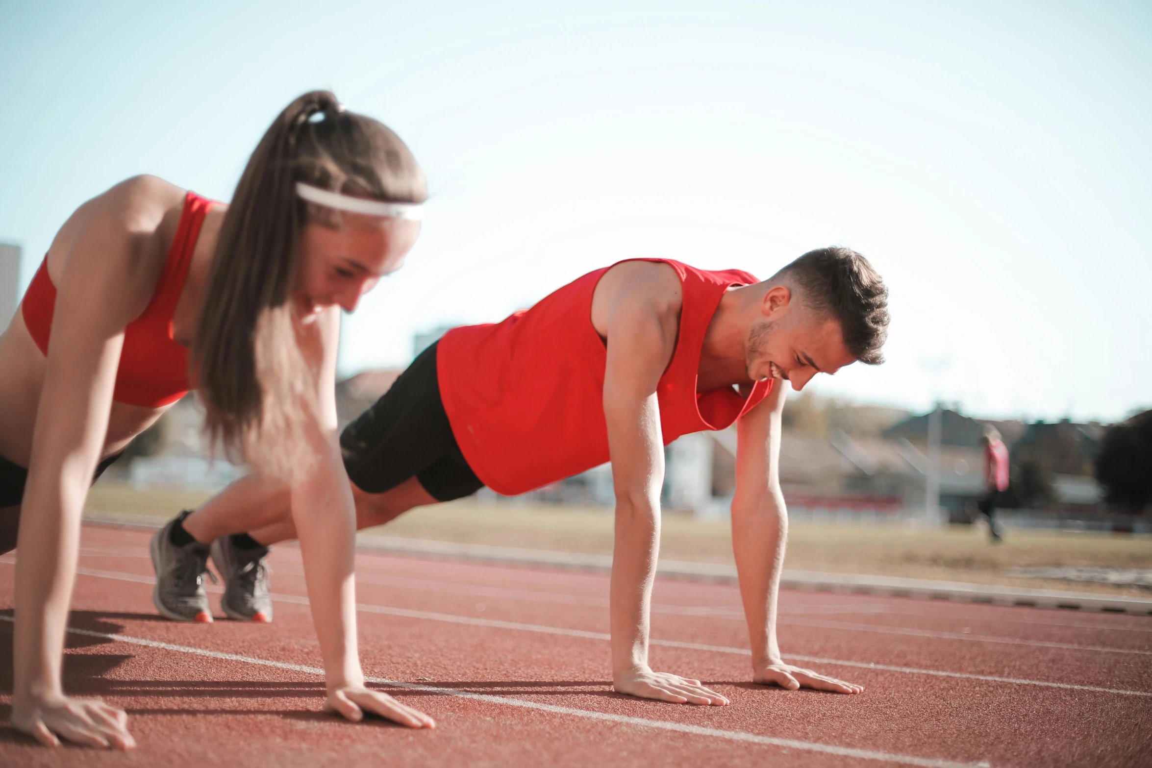 a man and a woman doing push ups on a track, pexels contest winner, wearing red shorts, outside on the ground, profile image, thumbnail