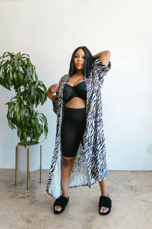 a woman standing next to a plant in a room, wearing two - piece swimsuit, in a black chiffon layered robe, zebra, serena williams