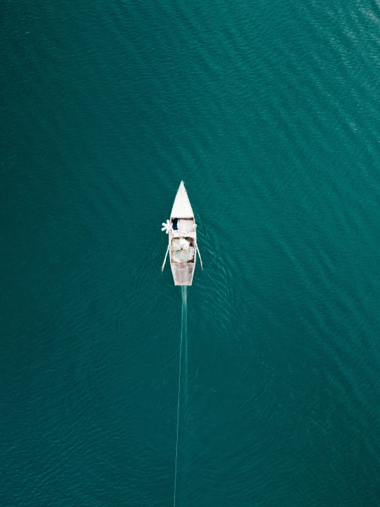 a small boat in the middle of a large body of water, pexels contest winner, head straight down, standing on the mast, teal aesthetic, top down camera angle