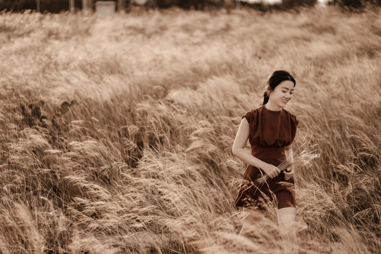 a woman standing in a field of tall grass, a picture, unsplash, visual art, korean audrey hepburn, background image, brown colours, hunting