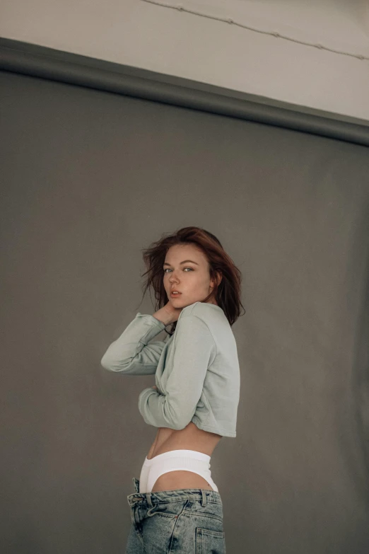 a woman standing in front of a garage door, inspired by Elsa Bleda, unsplash contest winner, photorealism, cropped shirt with jacket, grey backdrop, eleanor tomlinson, on a white table