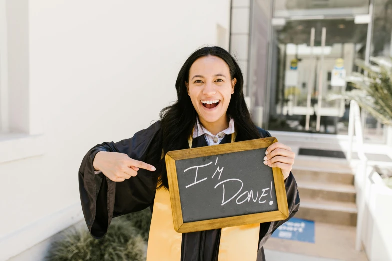 a woman in a graduation gown holding a sign, pexels contest winner, damien tran, blackboard, instagram post, triumphant pose