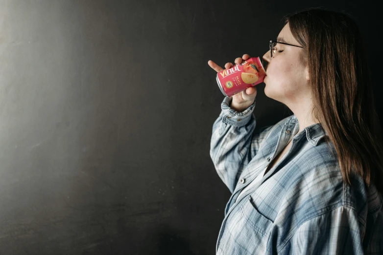 a woman drinking out of a pink donut, pexels contest winner, hyperrealism, soda cans, standing with a black background, wearing a red outfit, drinking cough syrup