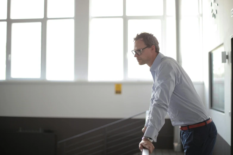 a man walking up a flight of stairs, by Jan Tengnagel, happening, in the office, thoughtful pose, man with glasses, promo image