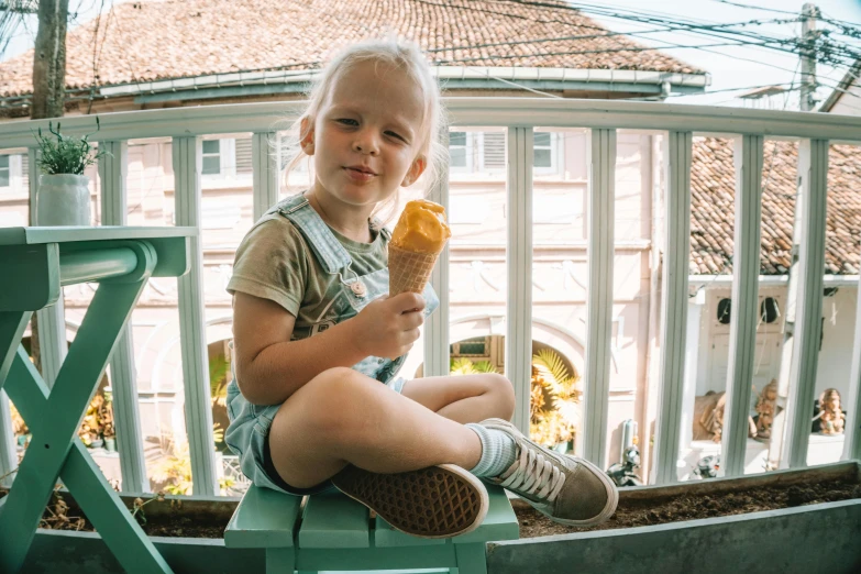 a little boy sitting on a chair eating an ice cream cone, by Emma Andijewska, pexels contest winner, girl sitting on a rooftop, blonde boy with yellow eyes, on a balcony, sitting on top of a cryopod