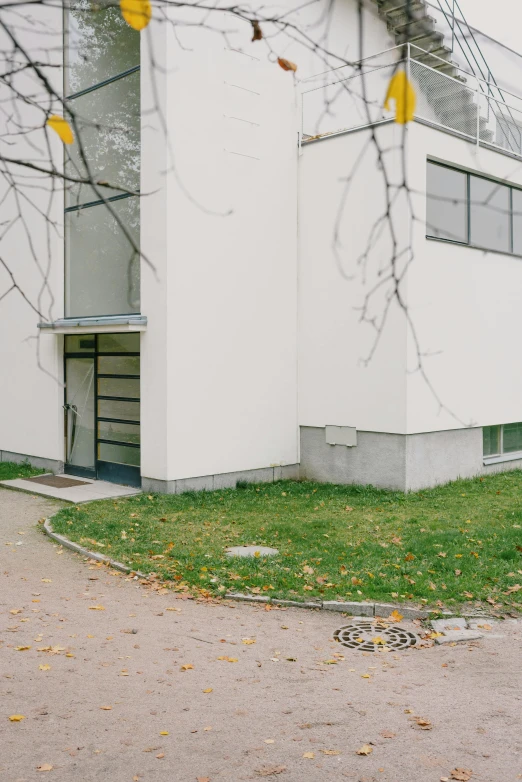 a red fire hydrant in front of a white building, by Bauhaus, bauhaus, small path up to door, alvar aalto, 2030s, autumn