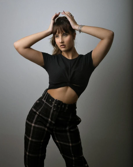 a woman posing with her hands on her head, by Robbie Trevino, wearing pants and a t-shirt, wearing a sexy cropped top, rugged black clothes, basia tran