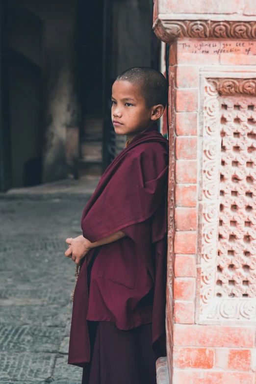 a young monk standing in front of a building, inspired by Steve McCurry, unsplash contest winner, maroon, kids, robes, looking serious