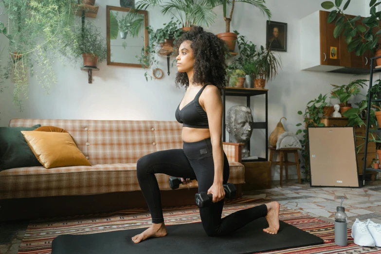 a woman standing on a yoga mat in a living room, pexels contest winner, arabesque, lifting weights, black leggins, thumbnail, tessa thompson inspired