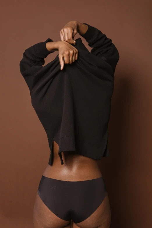 a woman in a black top and black panties, trending on pexels, arabesque, wearing sweatshirt, dark brown skin, cloaked woman, exposed midriff