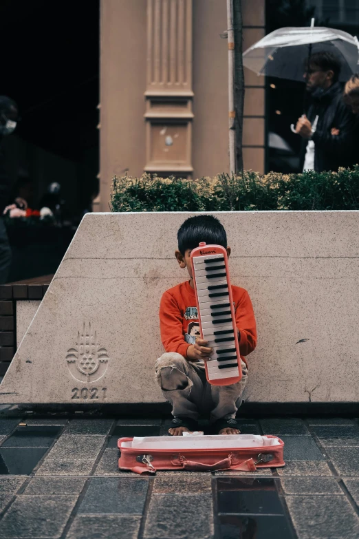 a little boy sitting on the ground with an accordion, pexels contest winner, in hong kong, xylophone, trending on artist, concerned
