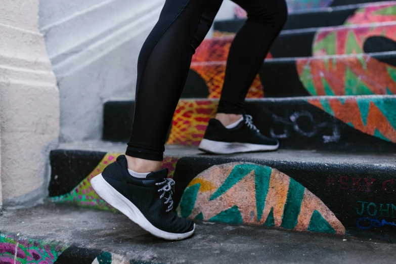 a person walking up a set of stairs, by Alice Mason, pexels contest winner, graffiti, wearing fitness gear, black shoes, manuka, jet black leggins